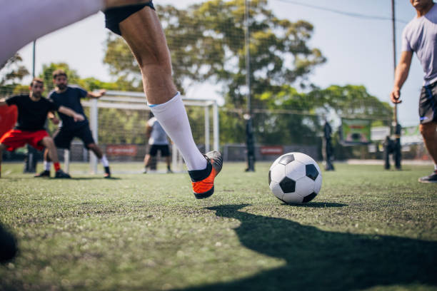 Group of men, male soccer players playing a match outdoors on soccer field.